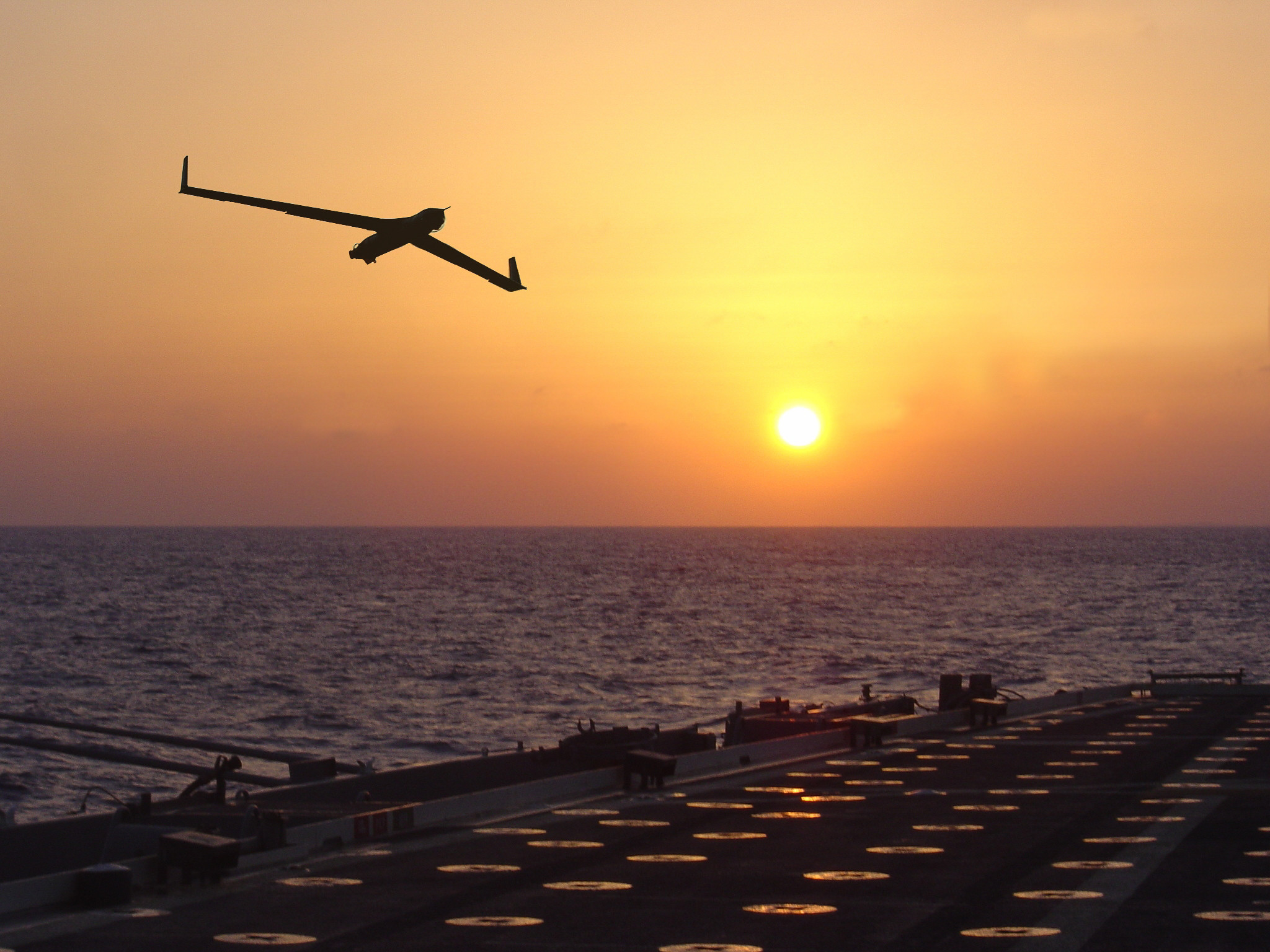 ScanEagle flying over a ship at sea.